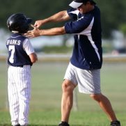 野球のコーチが子供に打ち方を伝えている